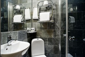 Een moderne badkamer met een douchecabine van glas, een witte wastafel en een toilet.