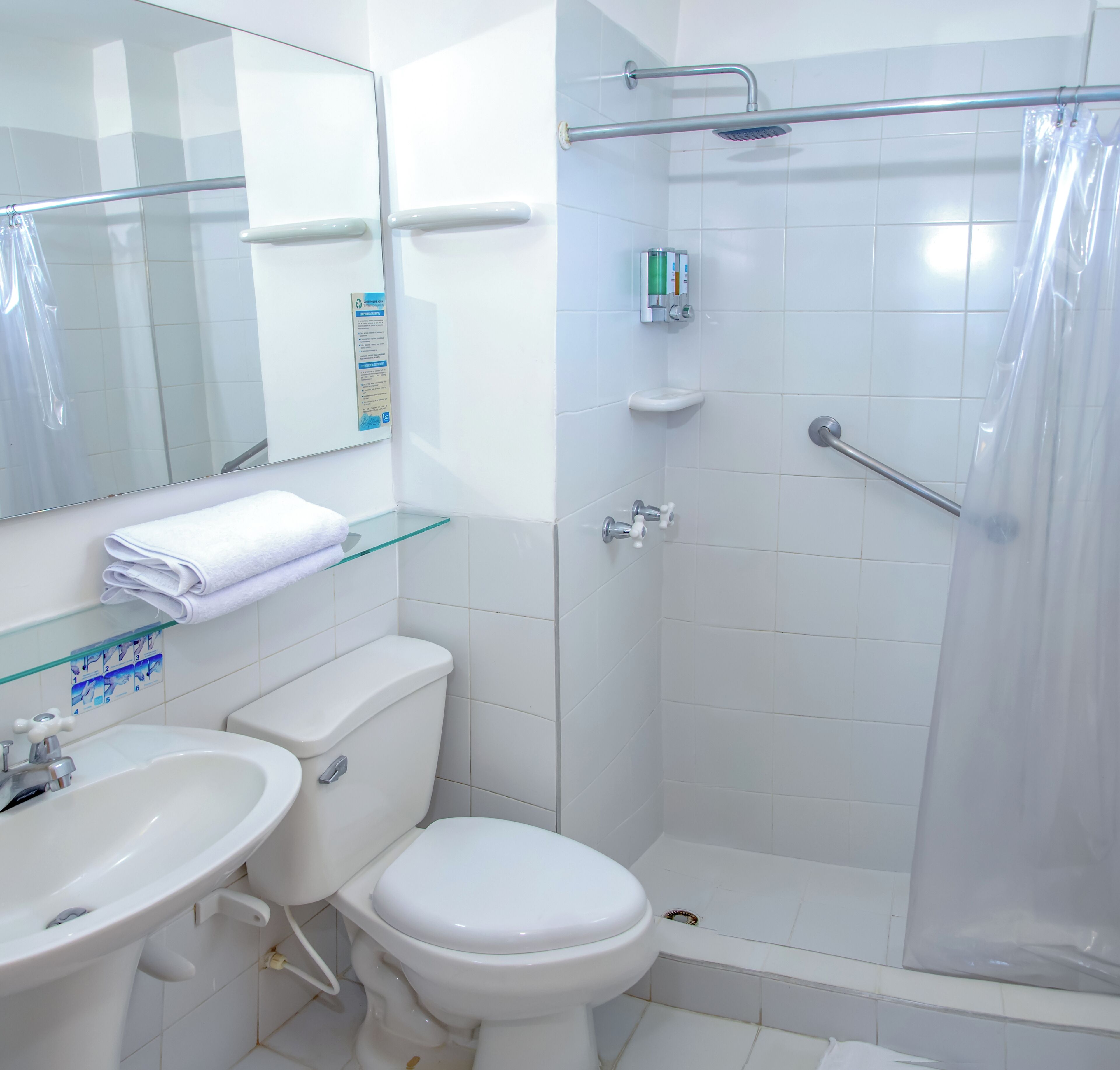 Un baño con inodoro, lavamanos y zona de ducha.
