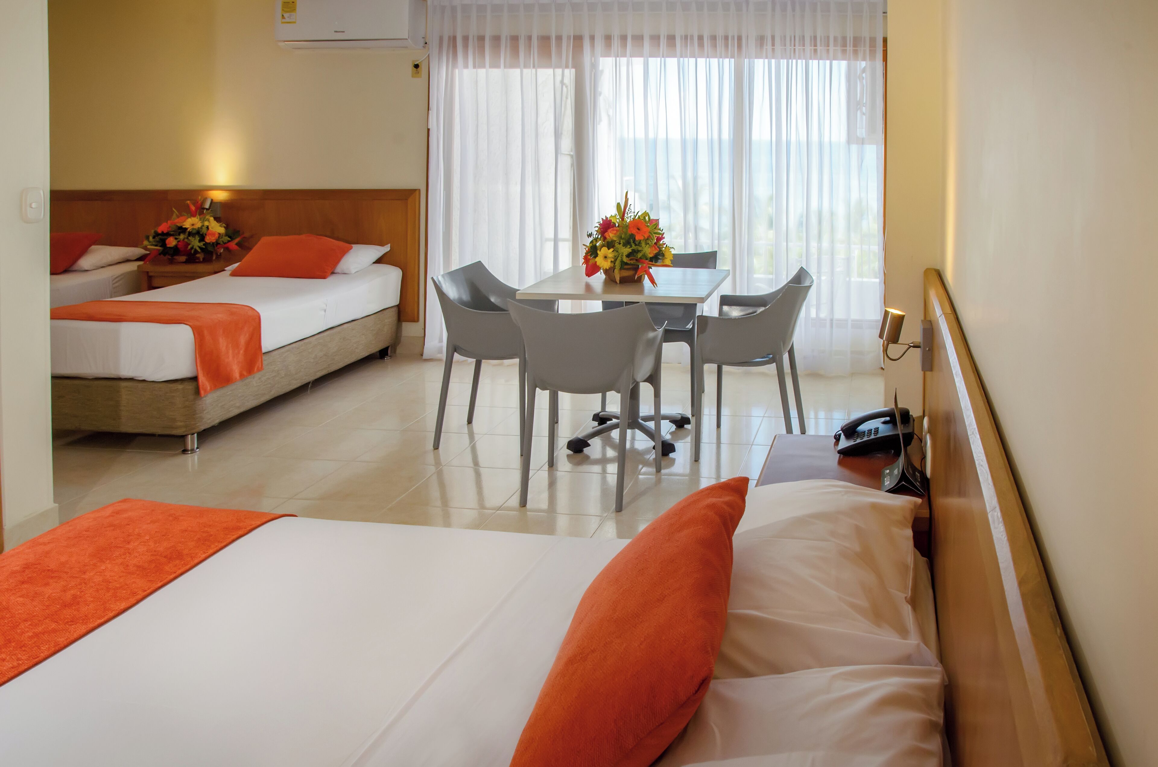 Una habitación de hotel con dos camas, una mesa de comedor con sillas y un teléfono.