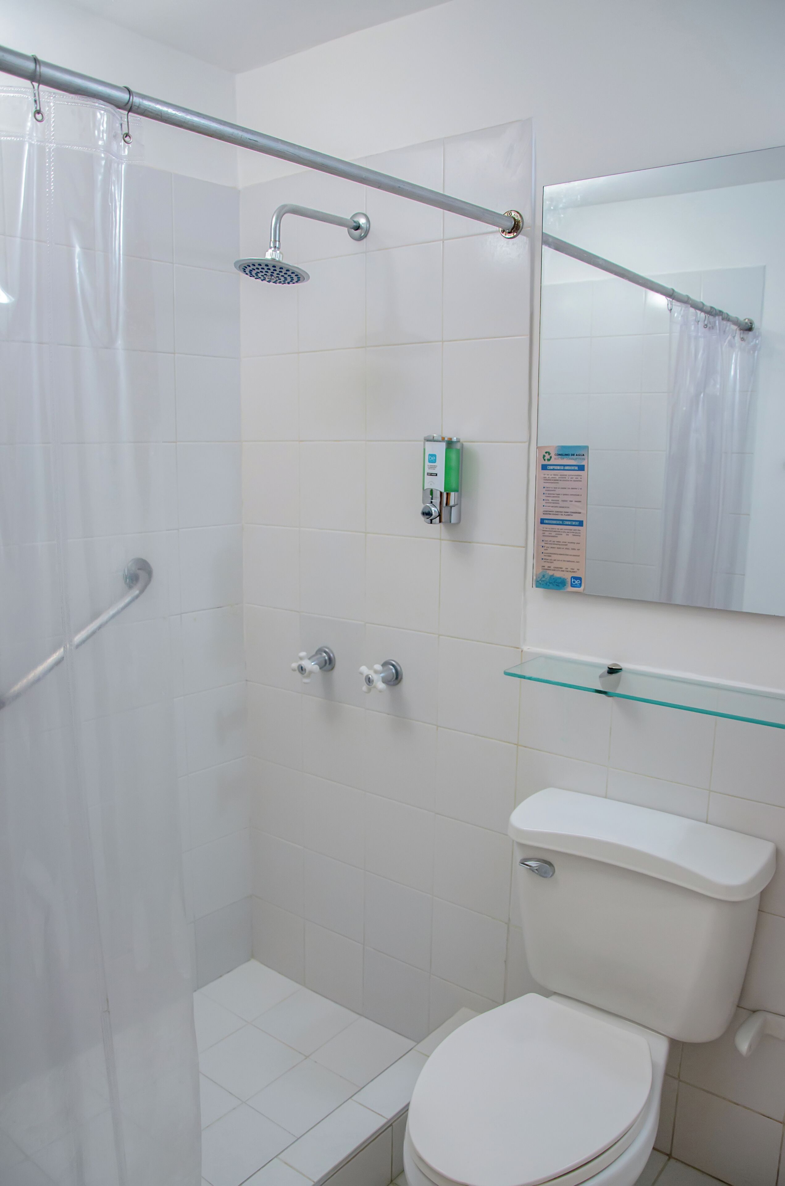 A bathroom with a shower, toilet, and glass shelf.