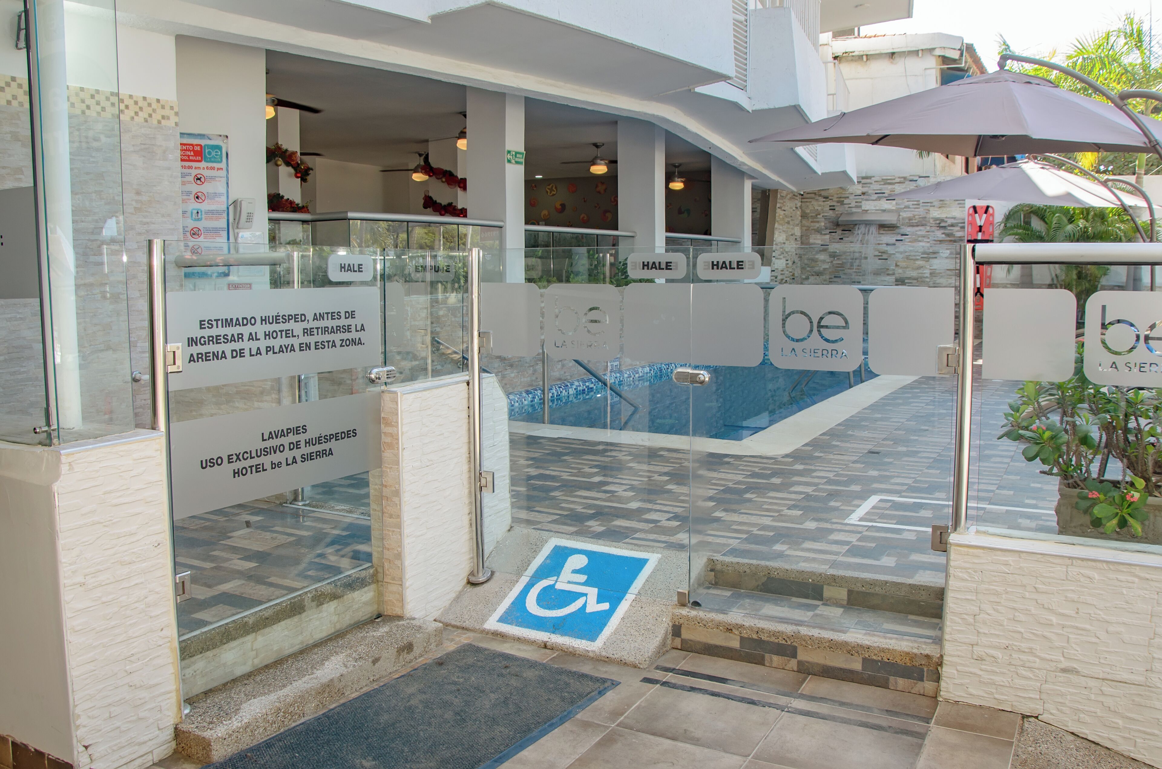 The entrance to a hotel with a glass door, a blue handicap accessibility symbol, and a sign indicating the use of the lavatories for hotel guests only.