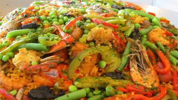 Una paella de mariscos grande y colorida, con diversas verduras y hierbas.