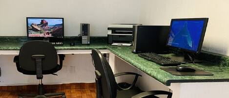 A reception area with a computer desk, two monitors, a printer, and a chair.
