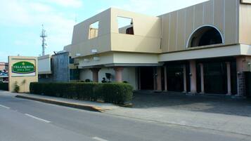 Un hôtel au design moderne, caractérisé par une enseigne bien visible, une grande entrée en arc de cercle et un parterre bien entretenu.