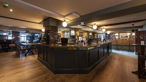 A bar area with a central counter, seating, and a brick wall.