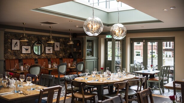 A restaurant with round tables, chairs, and hanging crystal chandeliers.