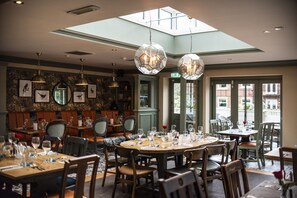 A restaurant with round tables, chairs, and hanging crystal chandeliers. - The Wilmslow Lodge (Wilmslow)