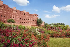 A large building with multiple windows and a garden with various colorful flowers in front. - Taj Devi Ratn Resort & Spa, Jaipur (Jaipur)