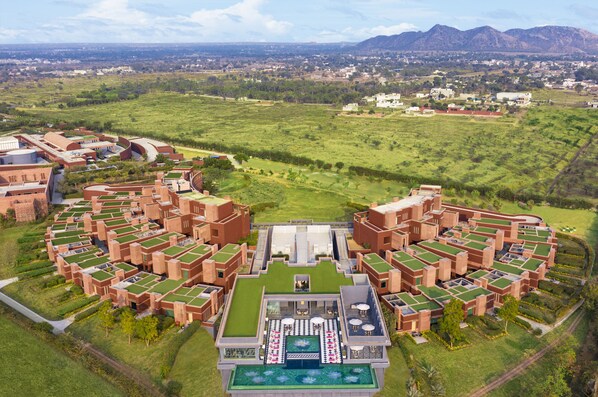 A resort with multiple buildings, a central pool area, and surrounding green fields. - Taj Devi Ratn Resort & Spa, Jaipur (Jaipur)