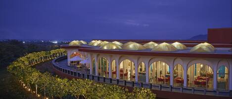 A hotel with a curved structure, large arched windows, and a series of covered outdoor seating areas.