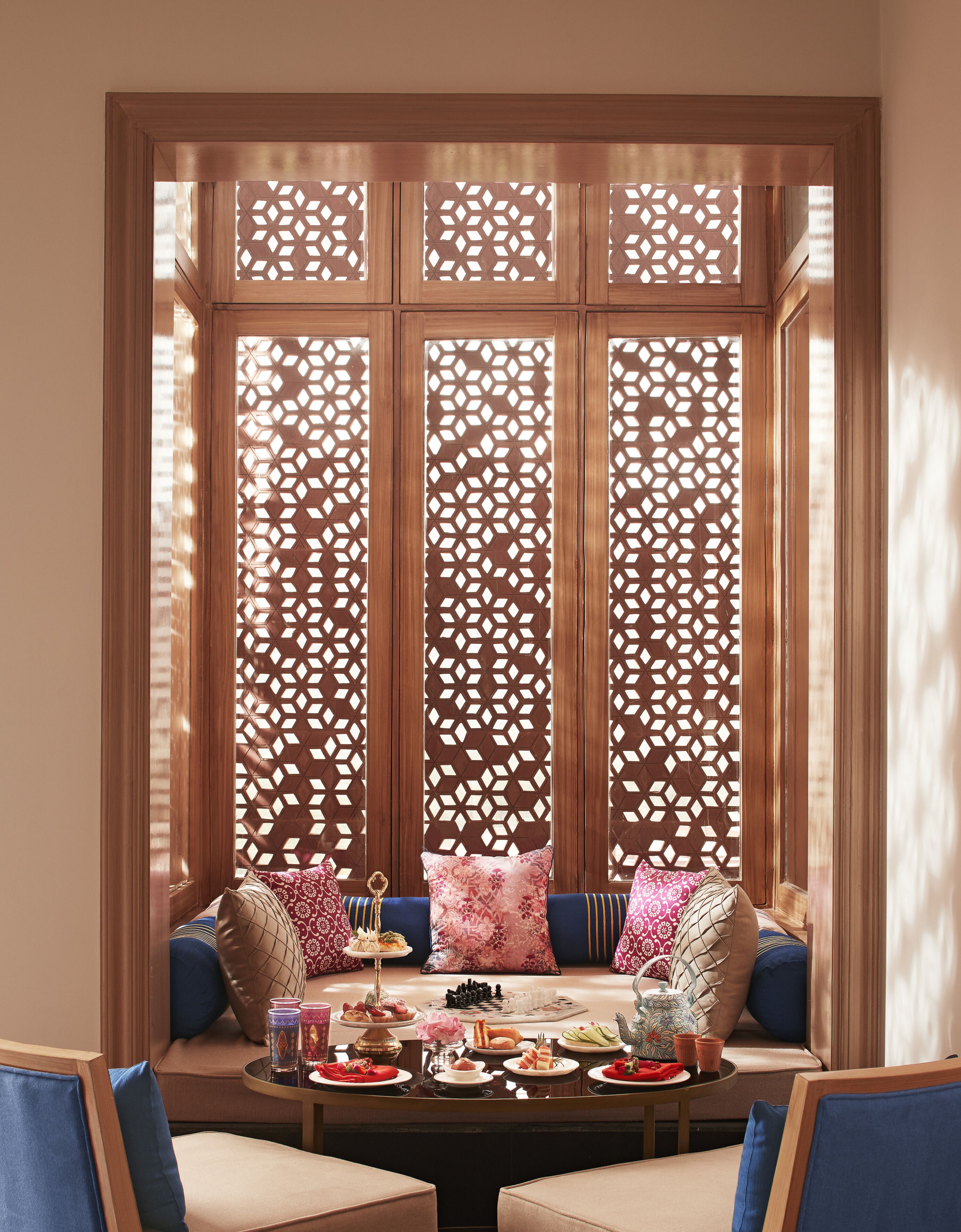 A room with a traditional wooden screen, a sofa with cushions, and a table set with food and drinks.