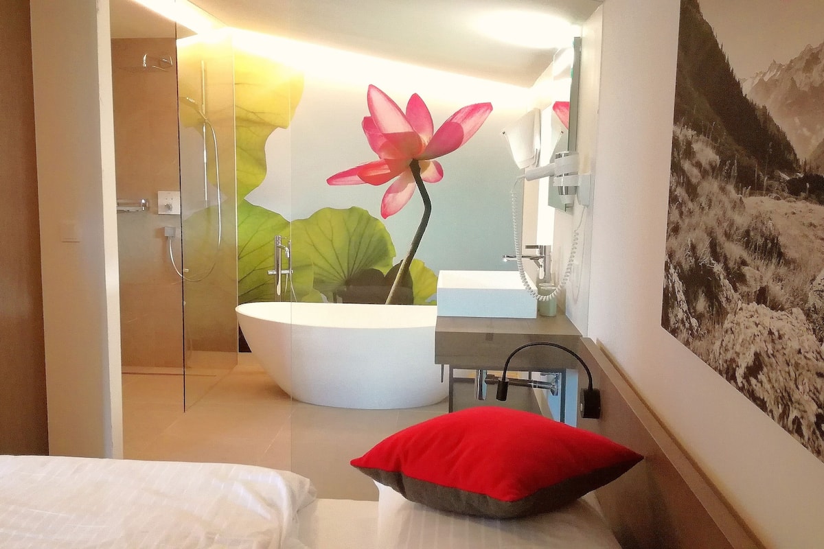 A modern bathroom with a large mirror, a bathtub, and a shower.