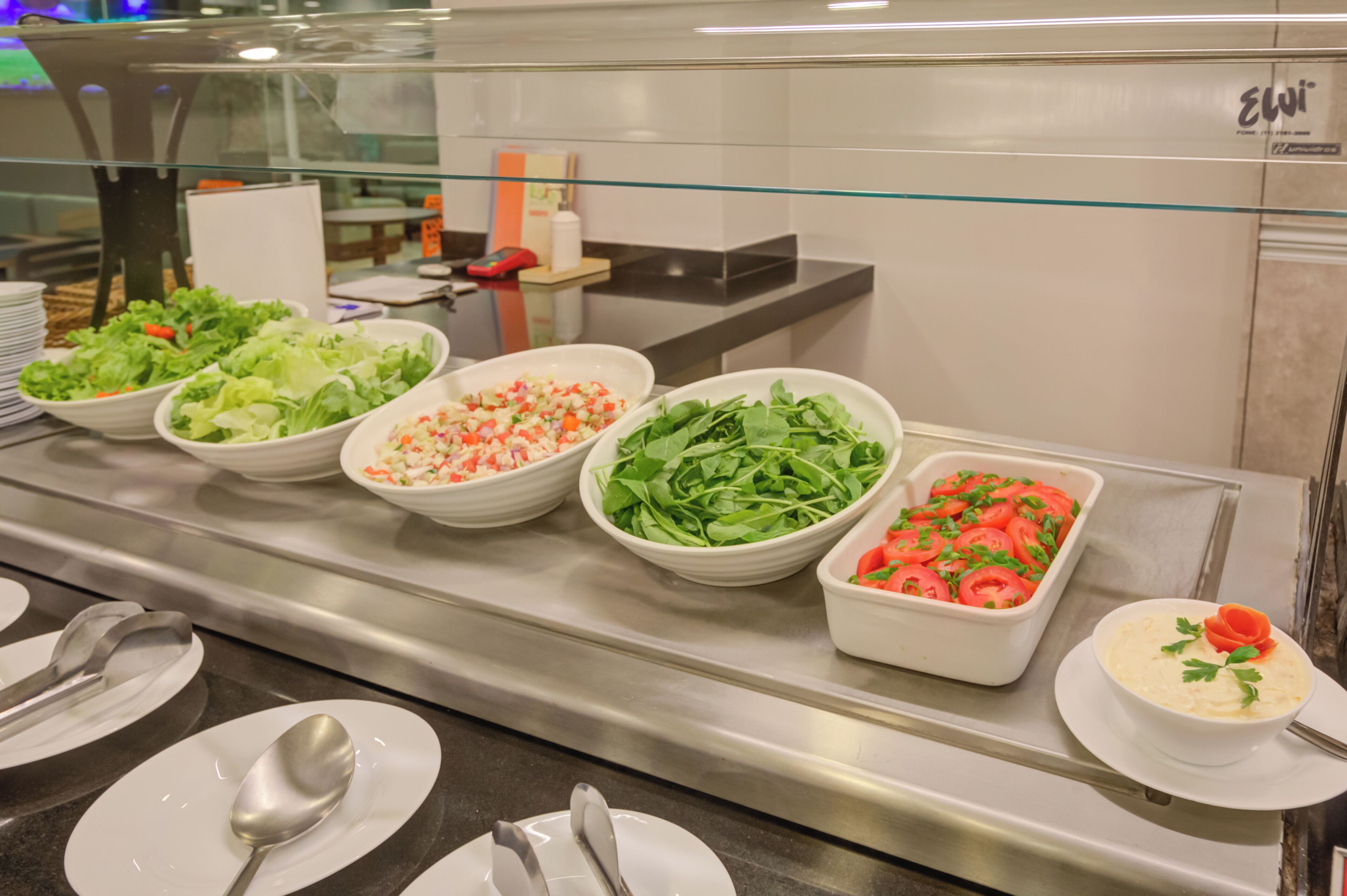 A buffet with various dishes including salads, a vegetable tray, and a bowl of soup.