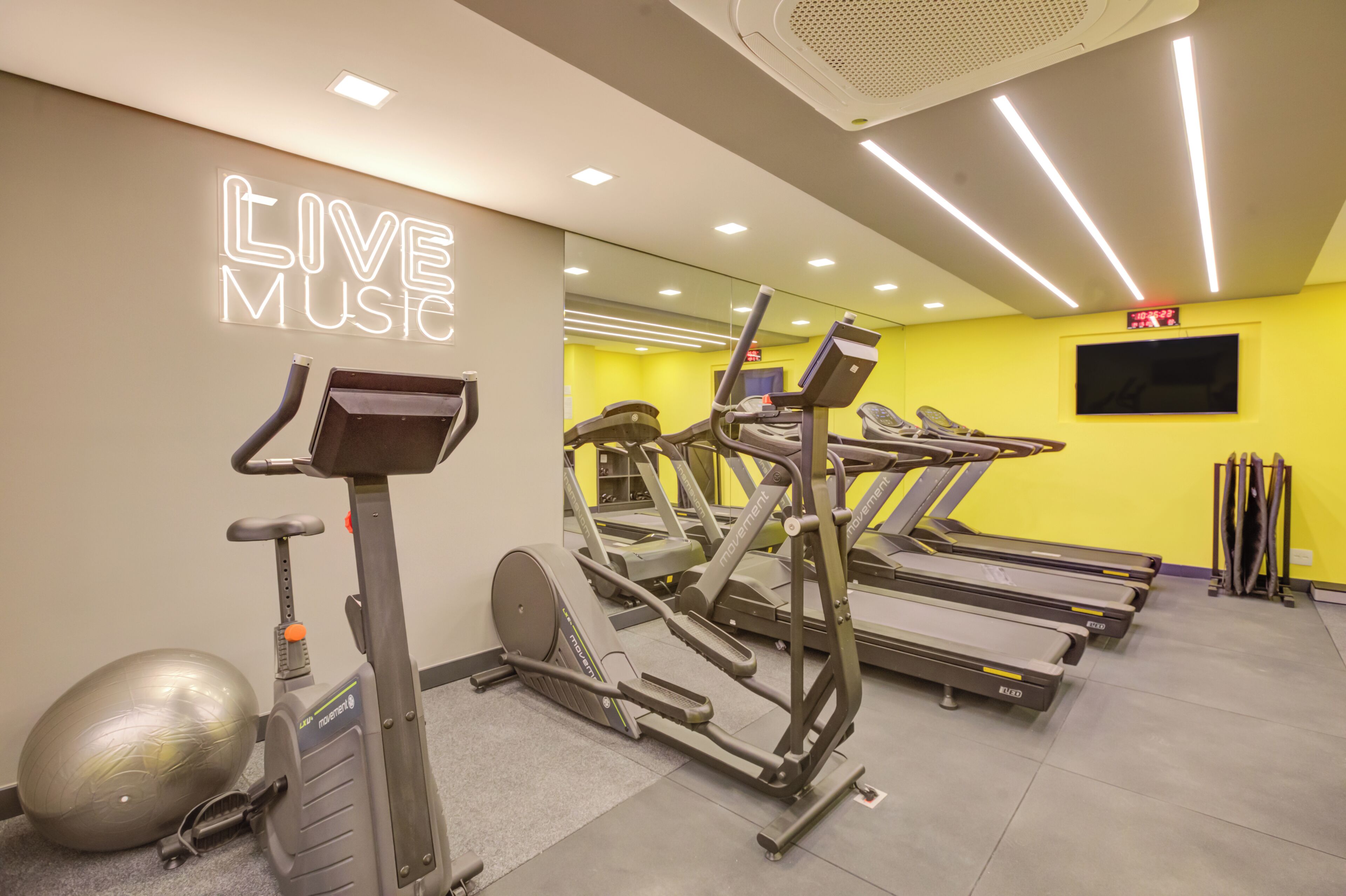 A gym with treadmills, exercise balls, and a 'LIVE MUSIC' sign.