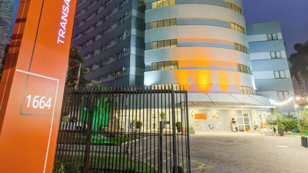 A modern hotel with a curved facade, a prominent entrance gate, and a sign indicating the address. - Transamerica Fit Villa Lobos (São Paulo)