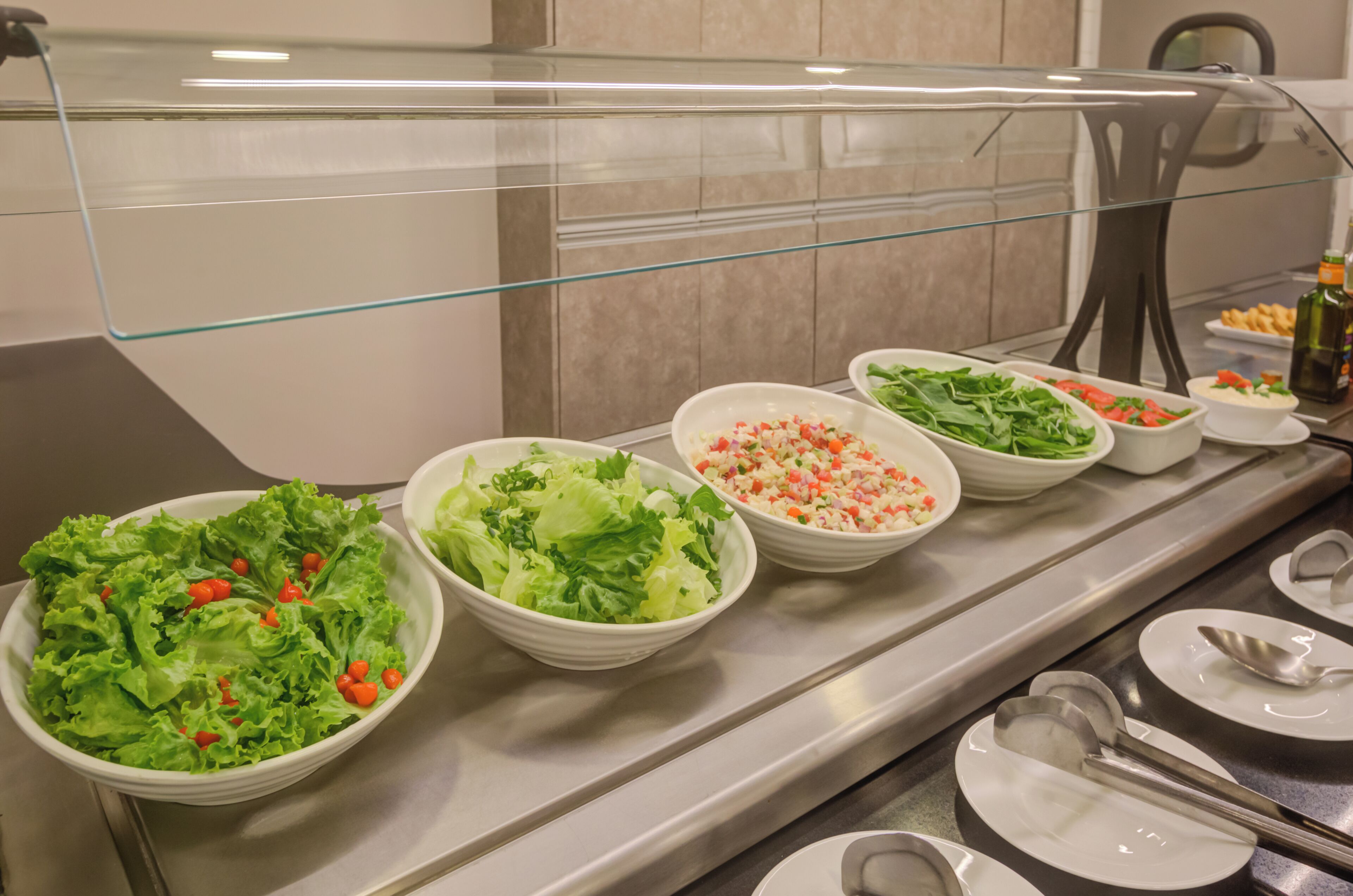 Un buffet proposant diverses salades et une bouteille d’huile d’olive.