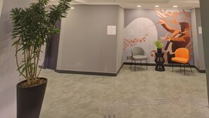 A modern lobby with a unique ceiling light fixture, a potted plant, and a mural on the wall. - Transamerica Fit Villa Lobos (São Paulo)