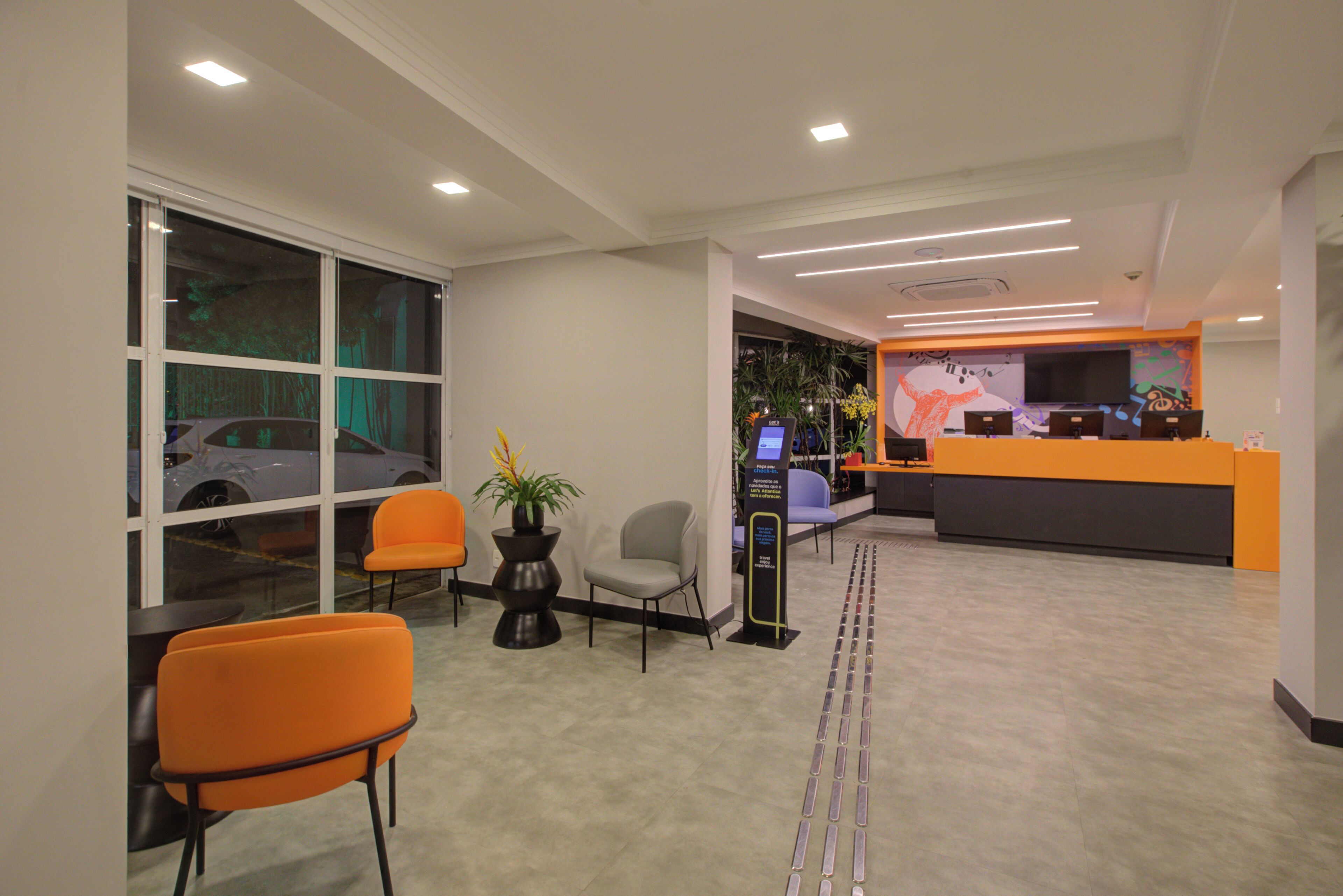 A reception area with a desk, chairs, a potted plant, and a large window.