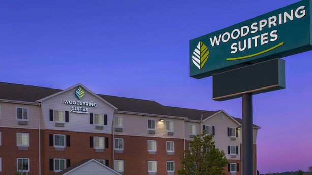 A multi-story hotel with a sign reading "Woodspring Suites". - WoodSpring Suites Omaha Bellevue, an Extended Stay Hotel (Bellevue)