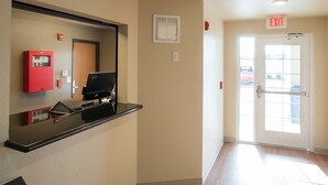 A hotel lobby with a reception desk, a fire alarm, an exit sign, and a door leading outside. - WoodSpring Suites Omaha Bellevue, an Extended Stay Hotel (Bellevue)