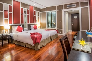 A hotel room with two beds, a dining table, and a large window with blinds. - Royal Lotus Hotel Halong (Ha Long)