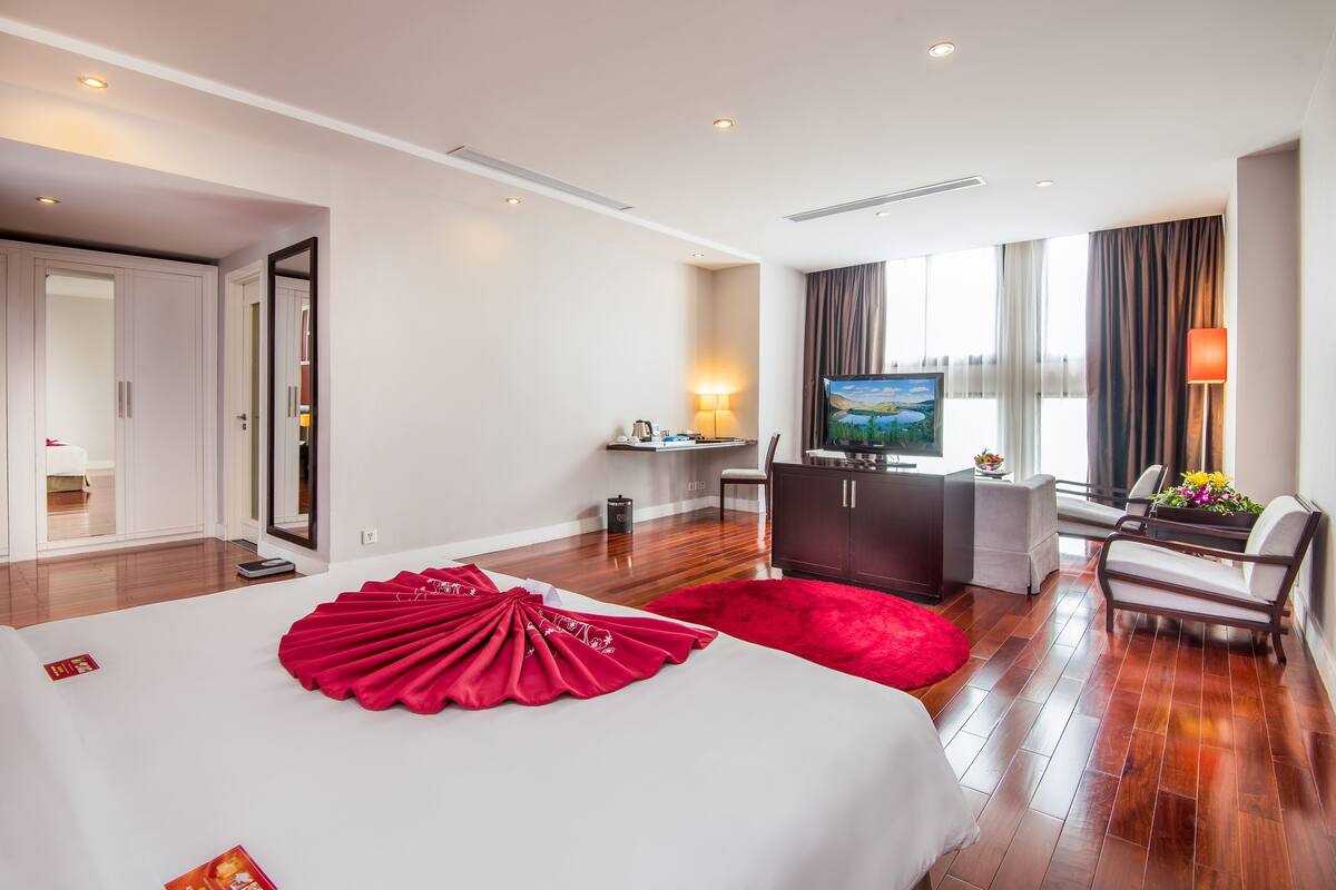 Une chambre d’hôtel avec un grand lit, un bureau, une télévision et une vue sur la ville.
