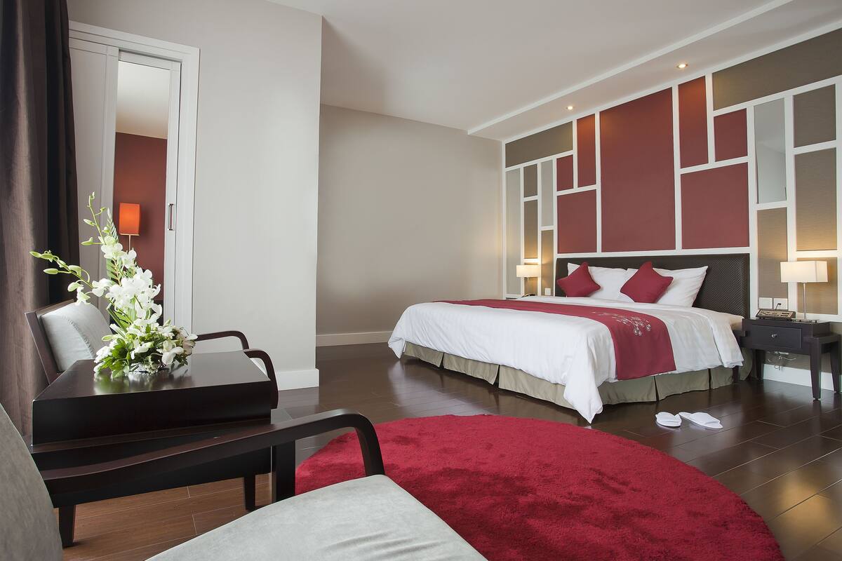 Une chambre d’hôtel avec un lit, des tables de chevet, un bureau et une chaise.