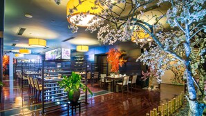 A restaurant with wooden flooring, tables, chairs, and a large potted plant. - Royal Lotus Hotel Halong (Ha Long)