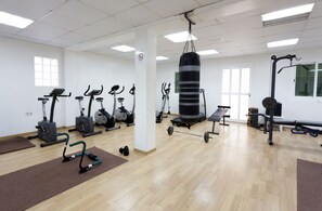 Une salle de sport équipée de divers appareils d’exercice, notamment des tapis de course, des vélos d’appartement et un sac de frappe.