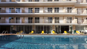 Un hotel con piscina, varios balcones y zonas de estar al aire libre.