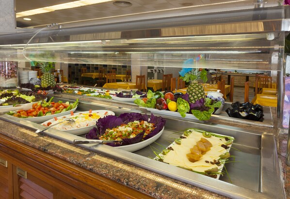 Un buffet proposant une variété de plats, notamment des salades, des fruits et des légumes.