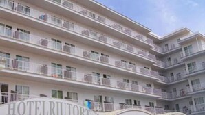 Un hotel de varios pisos con balcones en cada planta, un cartel que dice "HOTELRIUTORT" y una entrada cubierta.