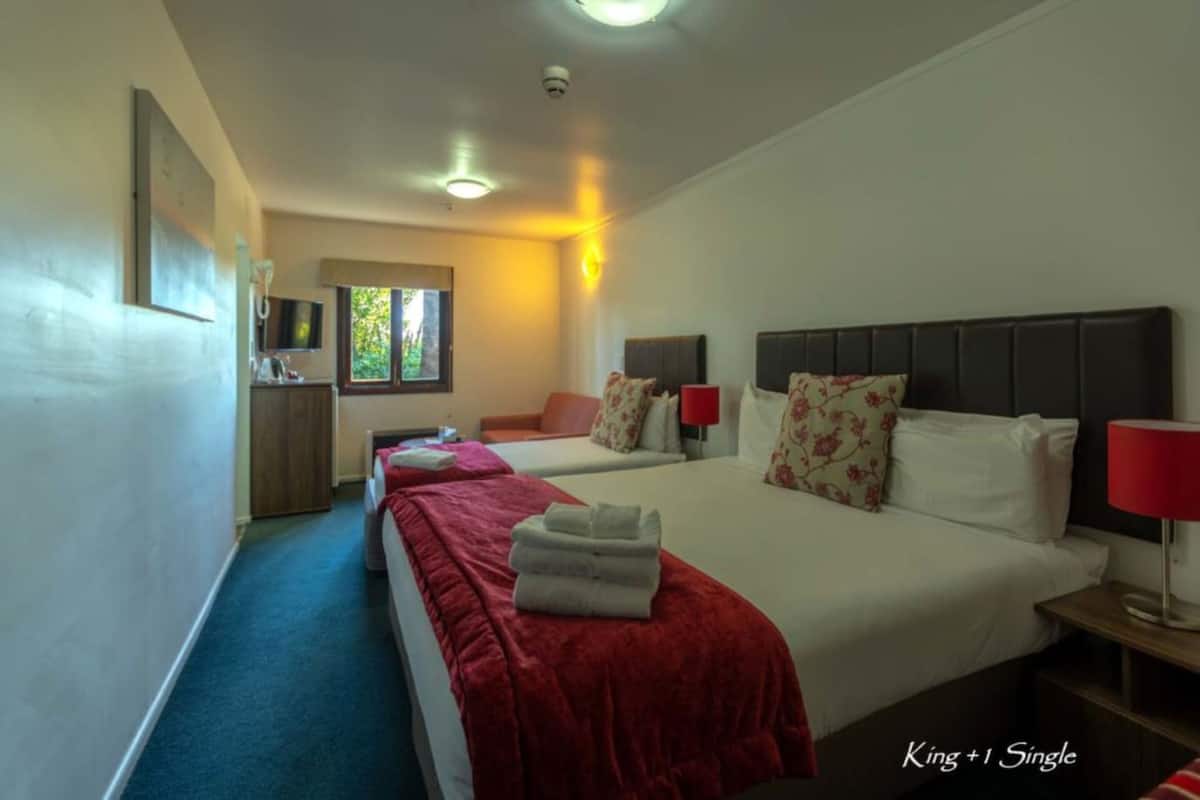 A hotel room with two beds, a TV, and a window.