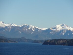 A mountain range with snow-capped peaks and a body of water in the foreground.