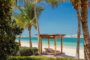 Praia particular, areia branca, espreguiçadeiras, guarda-sóis 