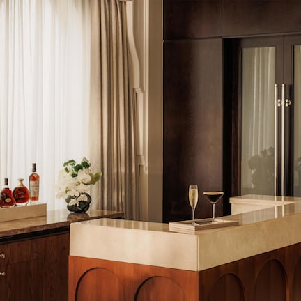 A modern bathroom with a large mirror, a vanity with a marble countertop, and a cabinet with wooden doors.