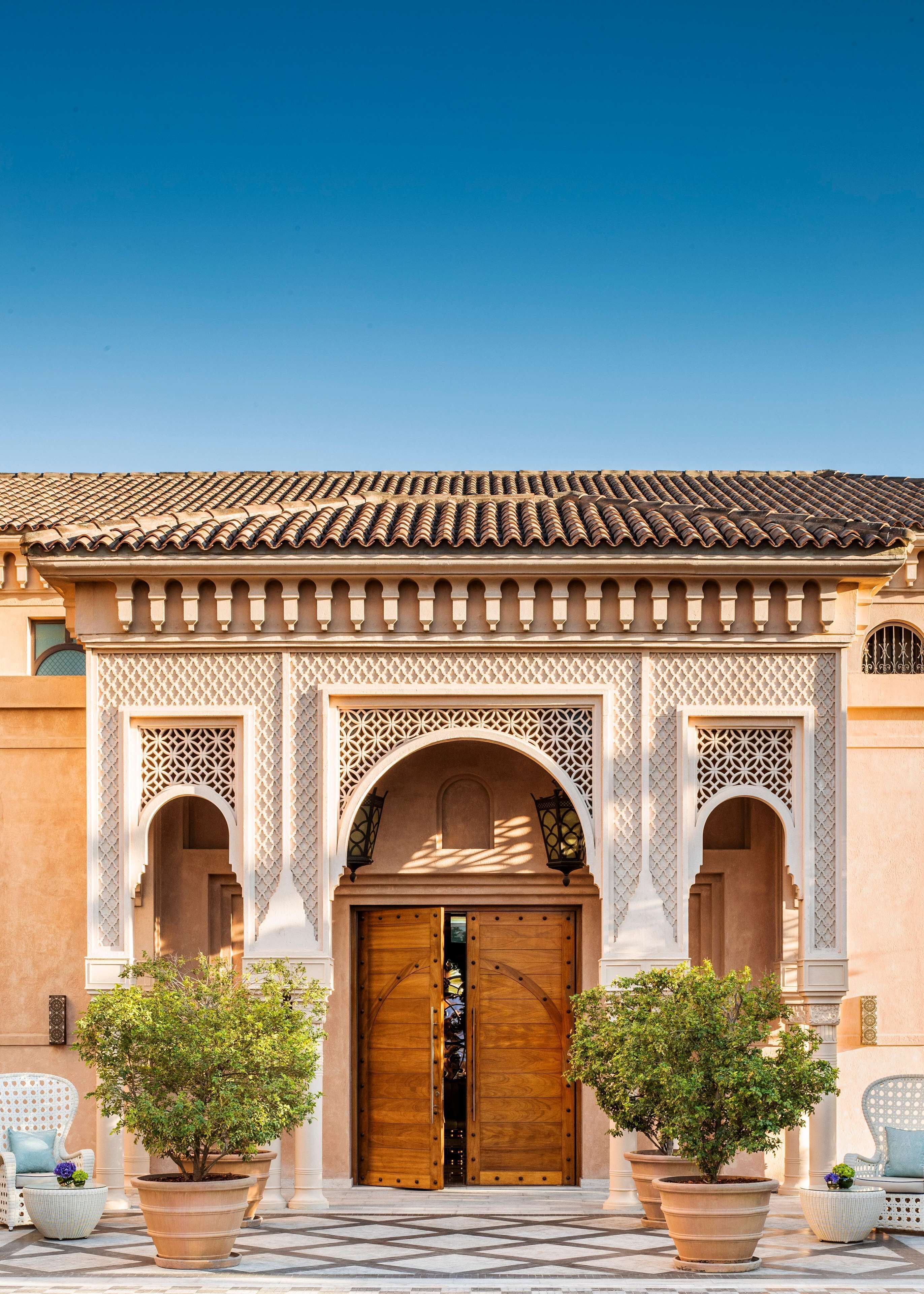 A building with a tiled roof, a wooden double door, and two potted plants.