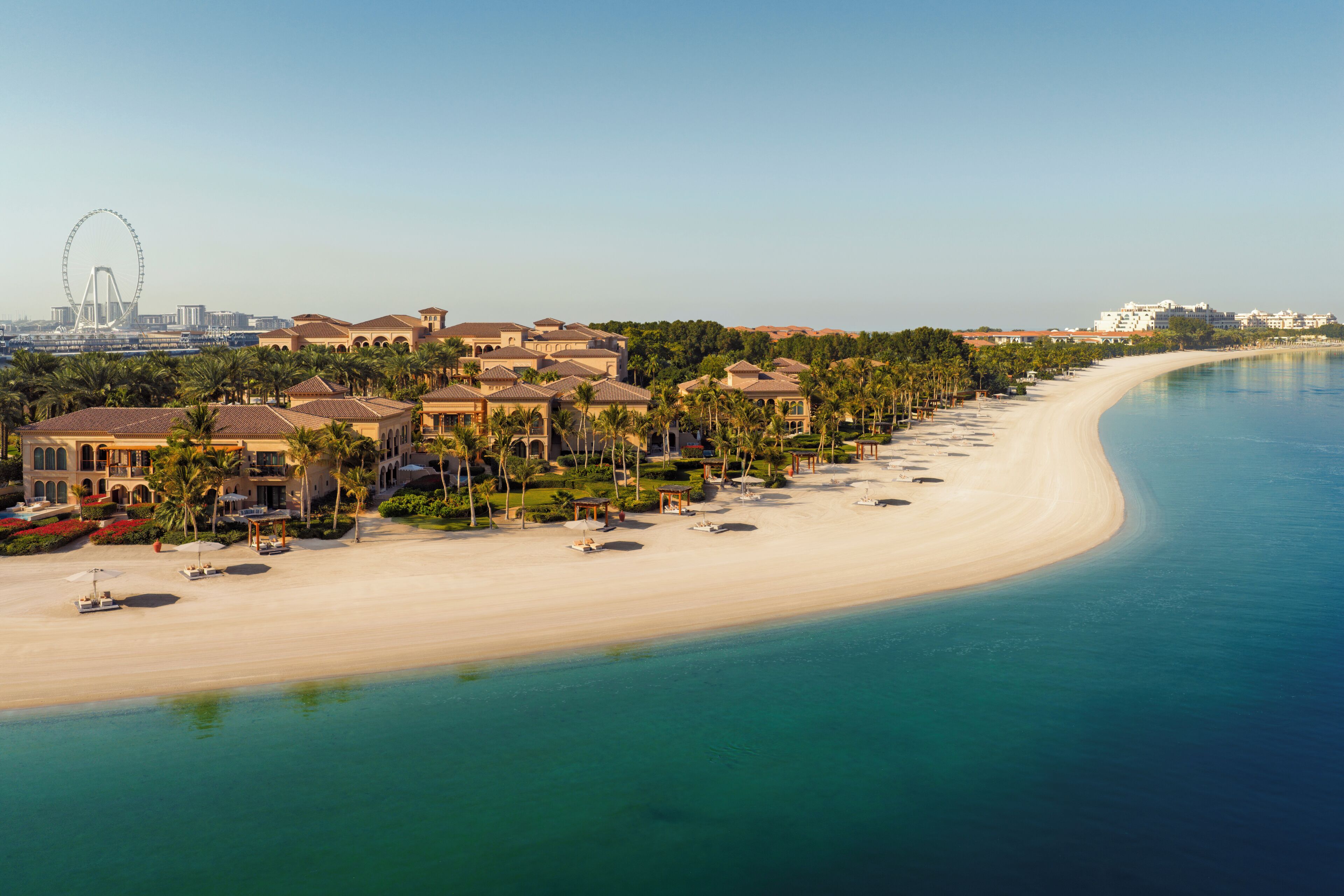 A coastal resort with beachfront villas, a sandy beach, and a clear view of the ocean.
