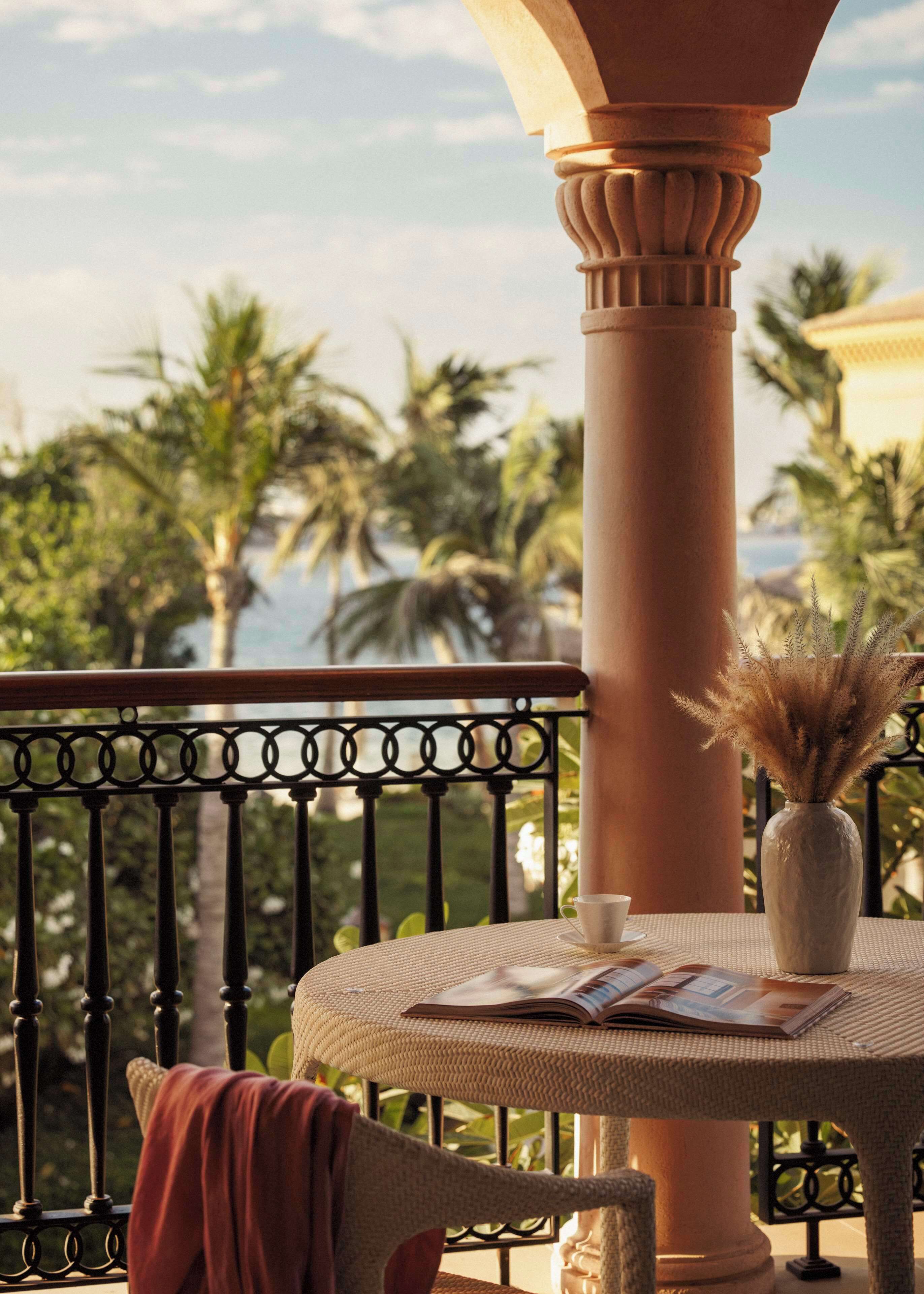 A balcony with a round table, a vase with dried plants, and a cushion.
