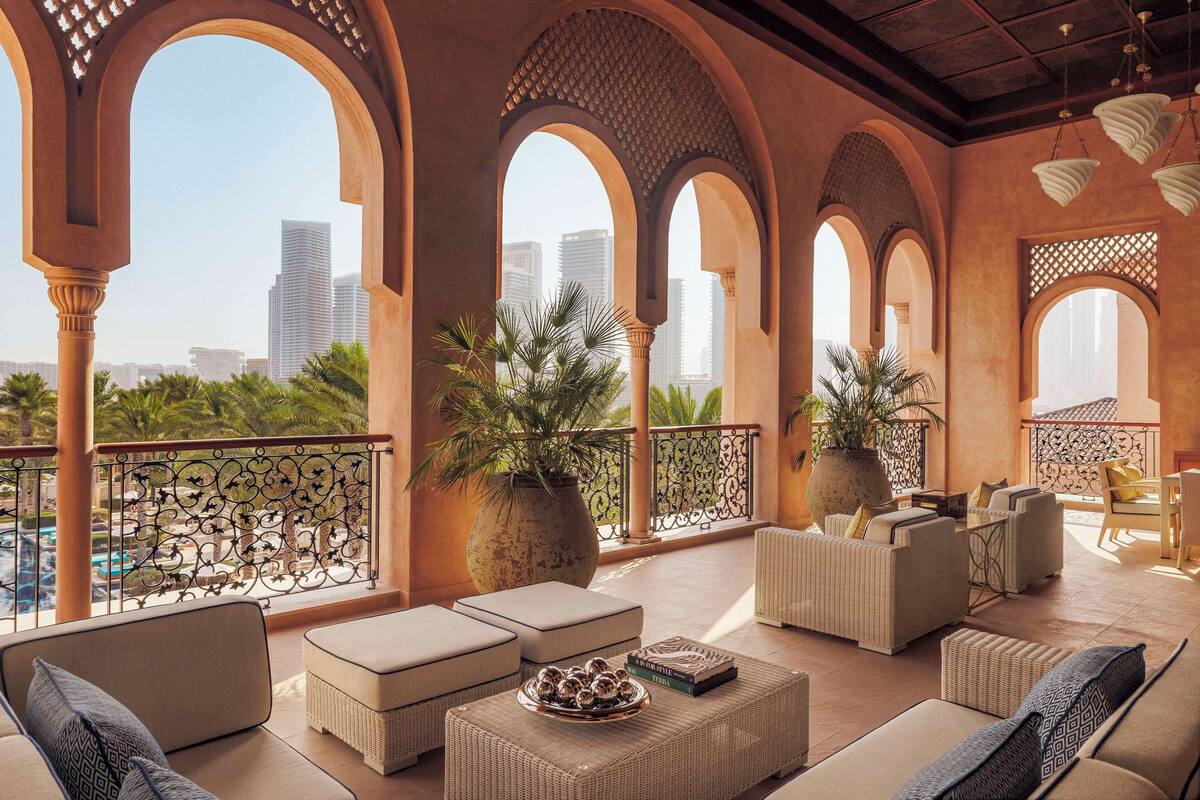 A spacious balcony with a view of the city skyline, furnished with sofas and a dining area.
