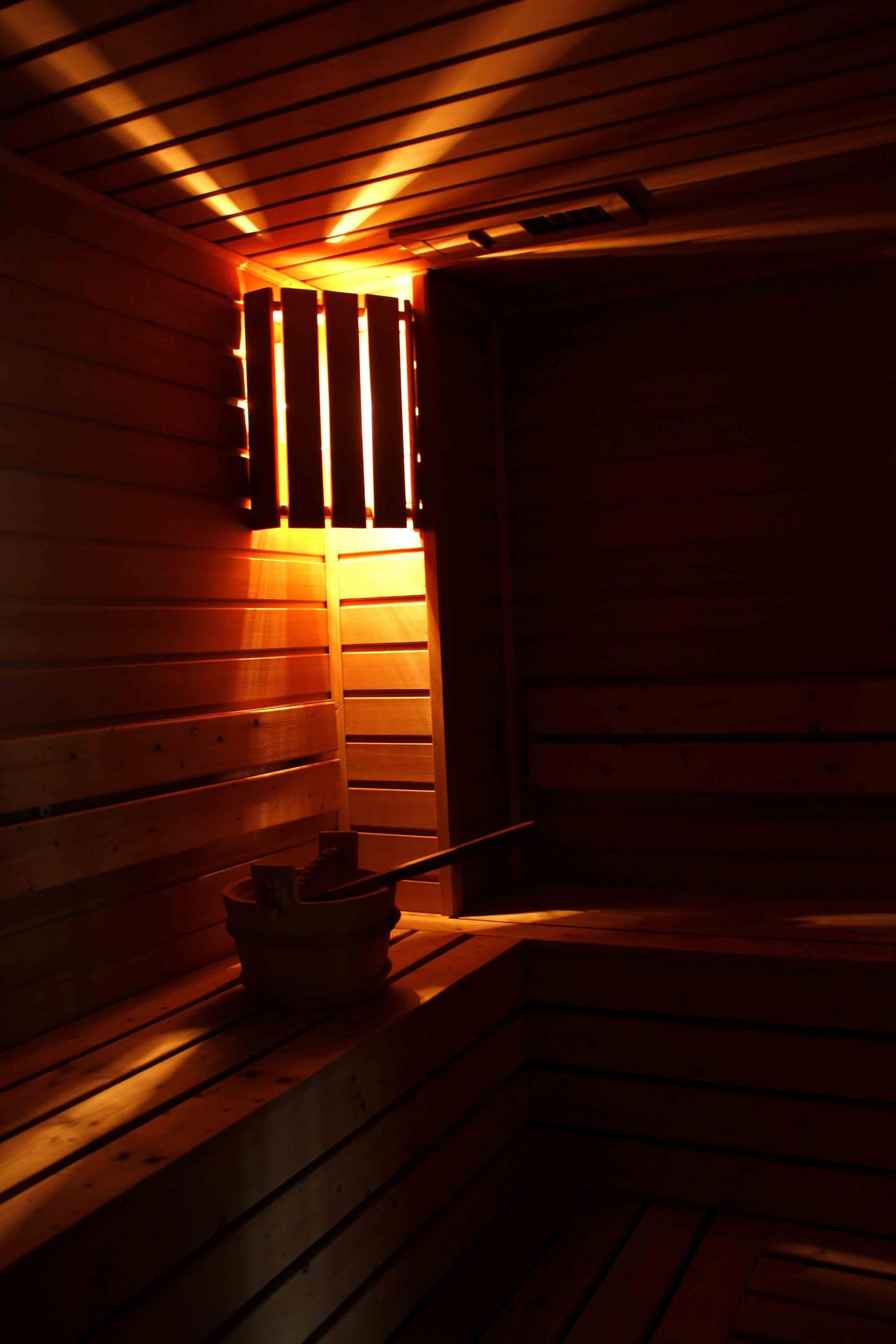 A sauna with wooden benches and a bench with a bowl.