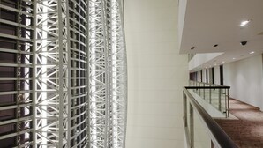 A modern interior with a curved metal structure, a wooden floor, and a glass railing overlooking a lower level. - IIDL Suites (New Delhi)