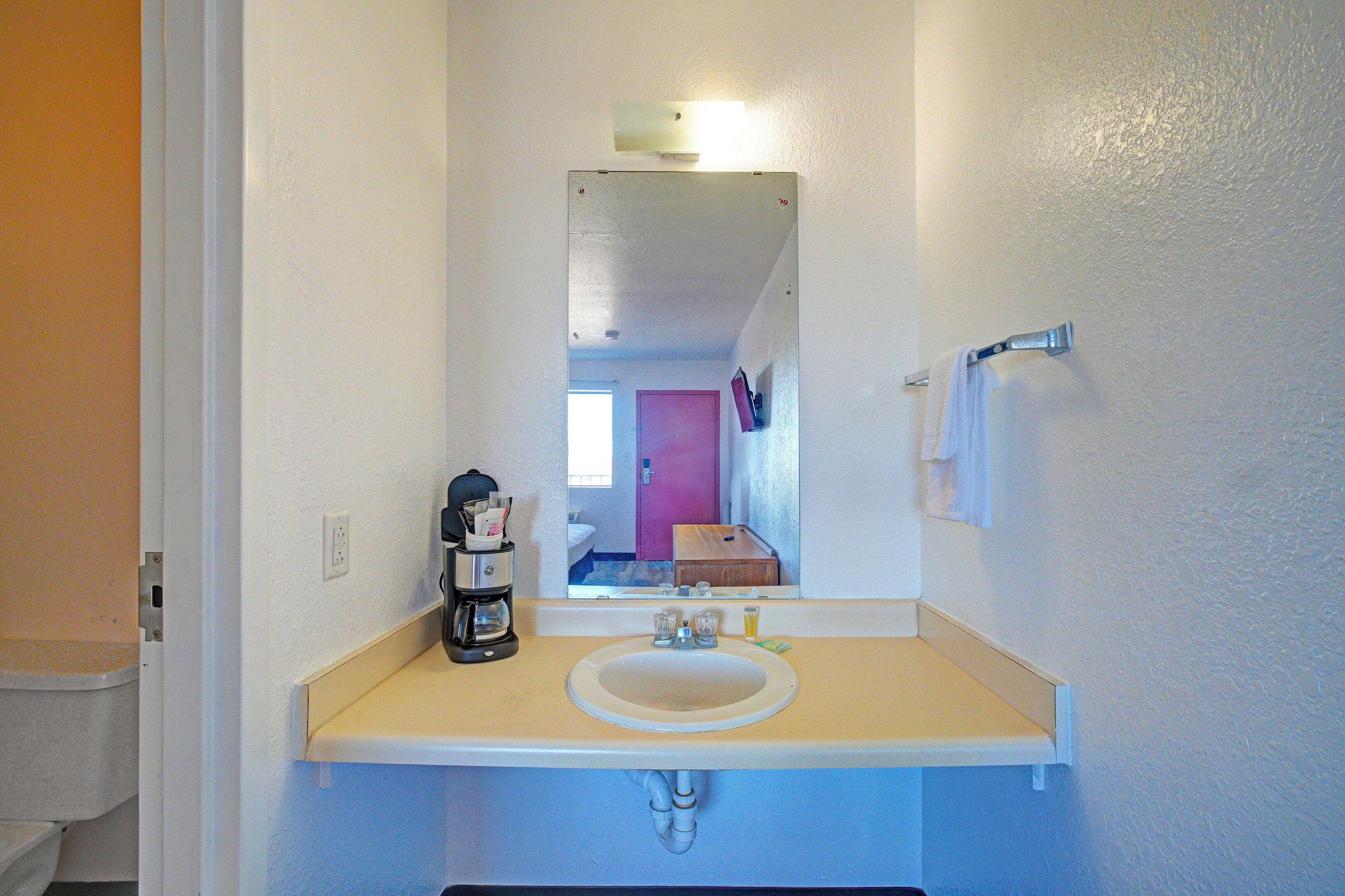 A bathroom with a sink, mirror, and a visible toilet.