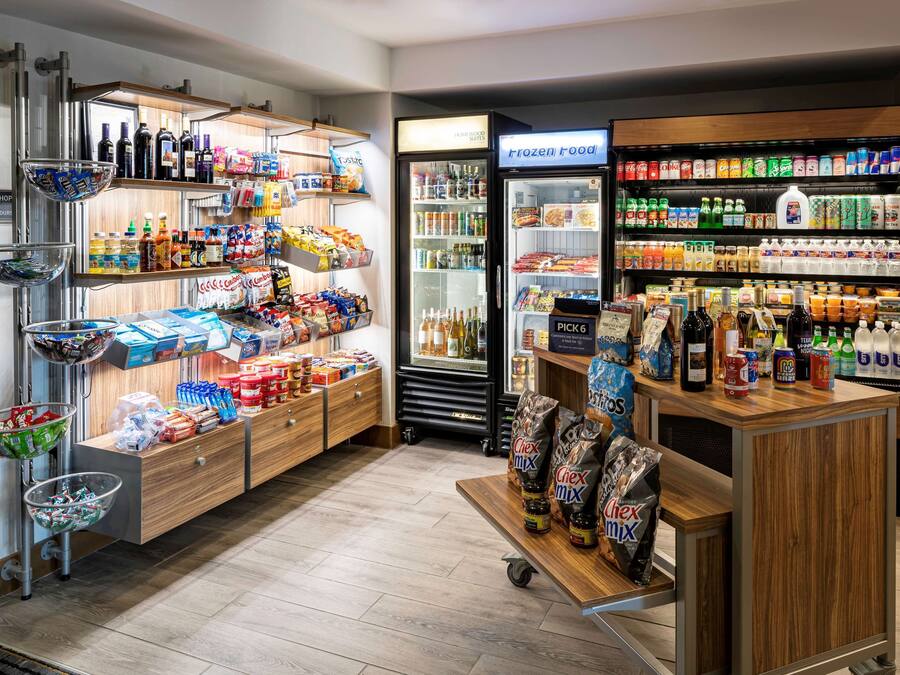 Una tienda de conveniencia con sección refrigerada, estantes llenos de aperitivos, bebidas y artículos para el hogar.
