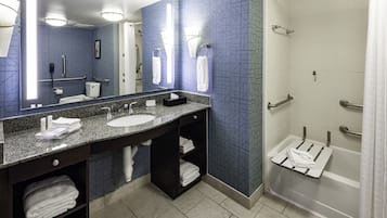 A modern bathroom with a large mirror, two sinks, a shower, and a towel rack.