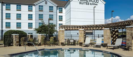 Een buitenzwembad, ligstoelen bij het zwembad