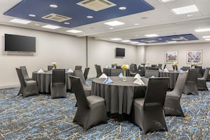 A conference room with round tables, chairs, and a flat-screen TV on the wall. - Hampton Inn & Suites Cincinnati/Uptown-University Area (Cincinnati)