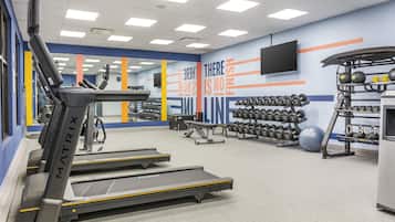 Un gimnasio con cintas de correr, mancuernas y pelotas de ejercicio.