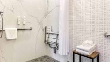 Un baño con ducha, un perchero y una mesita con toallas.