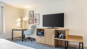 A hotel room with a bed, a desk, a chair, a television, a microwave, and a coffee maker.